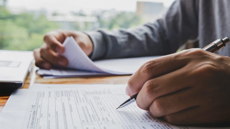 Closeup of man hand filling income tax forms